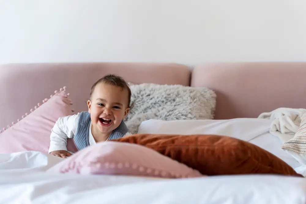 laughing-baby-laying-bed.webp